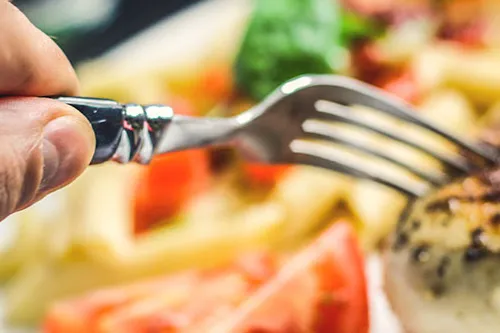 hand holding fork piercing a slice of roast turkey