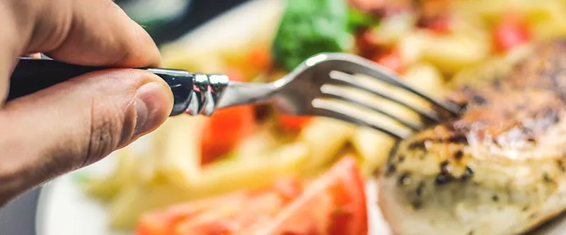 hand holding fork piercing a slice of roast turkey